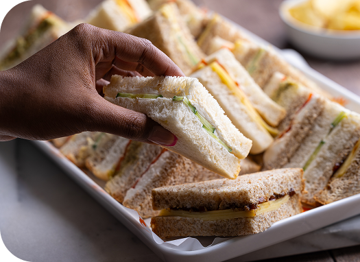 Wenzel’s Veggie Sandwich Platter with a cream cheese and cucumber sandwich held up from the tray